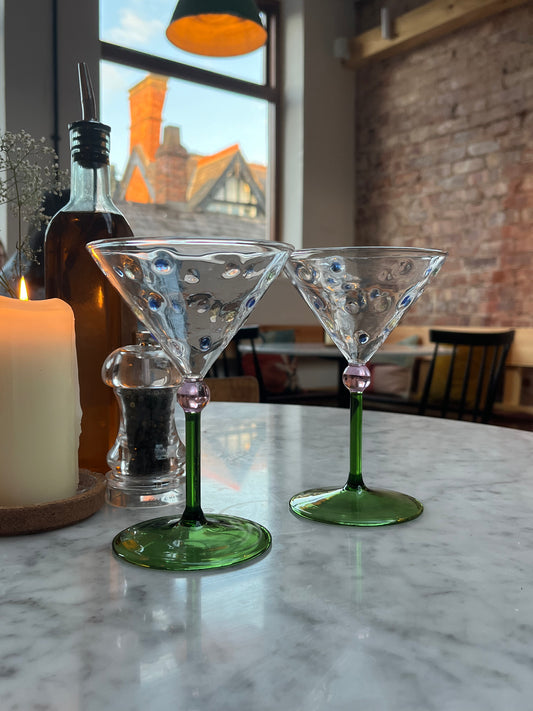 Front facing Image of two unique Martini cocktail glasses on a marble table setting 