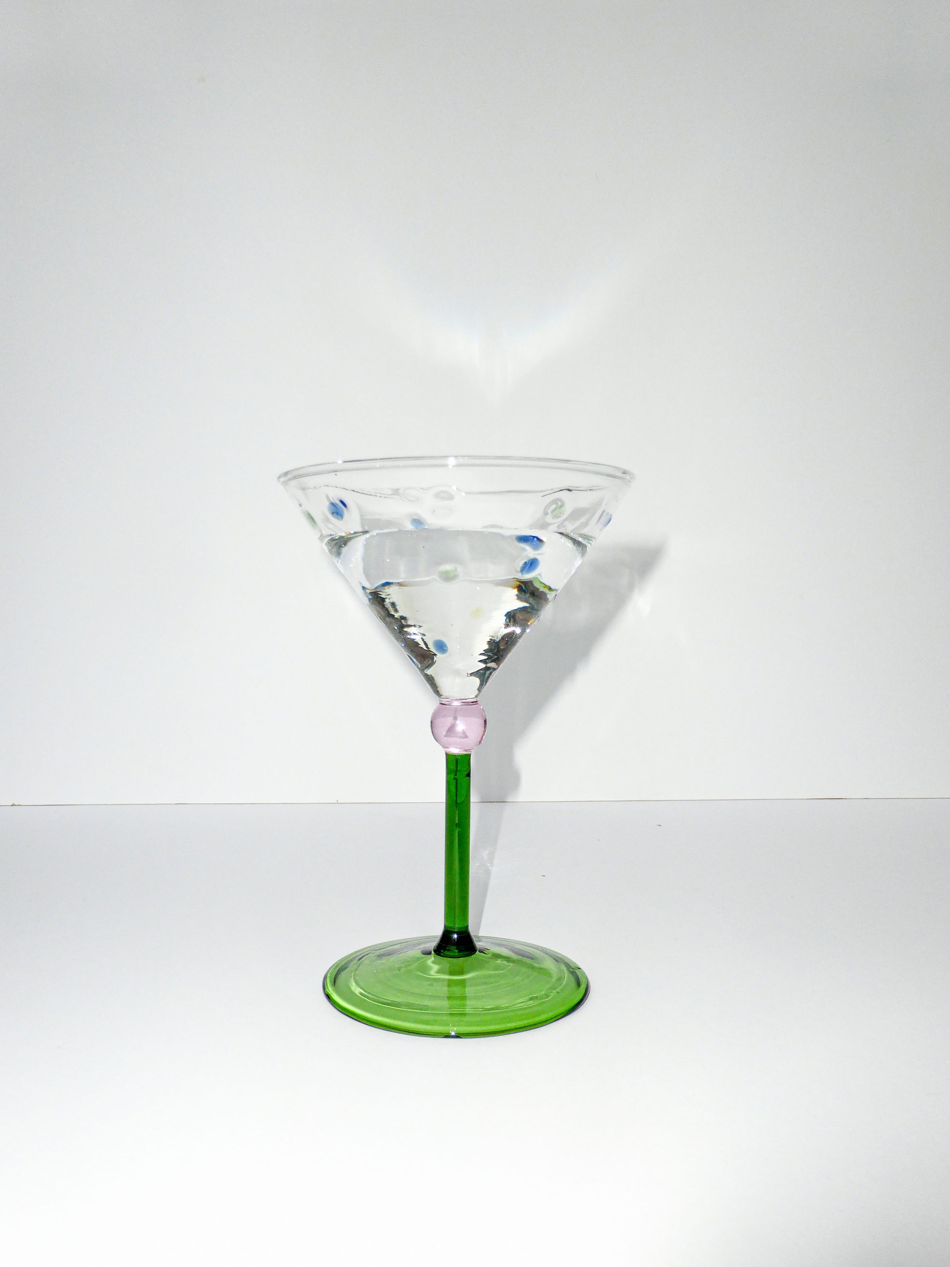 front facing image of one martini glass with green stem and colourful polka dot detailing  