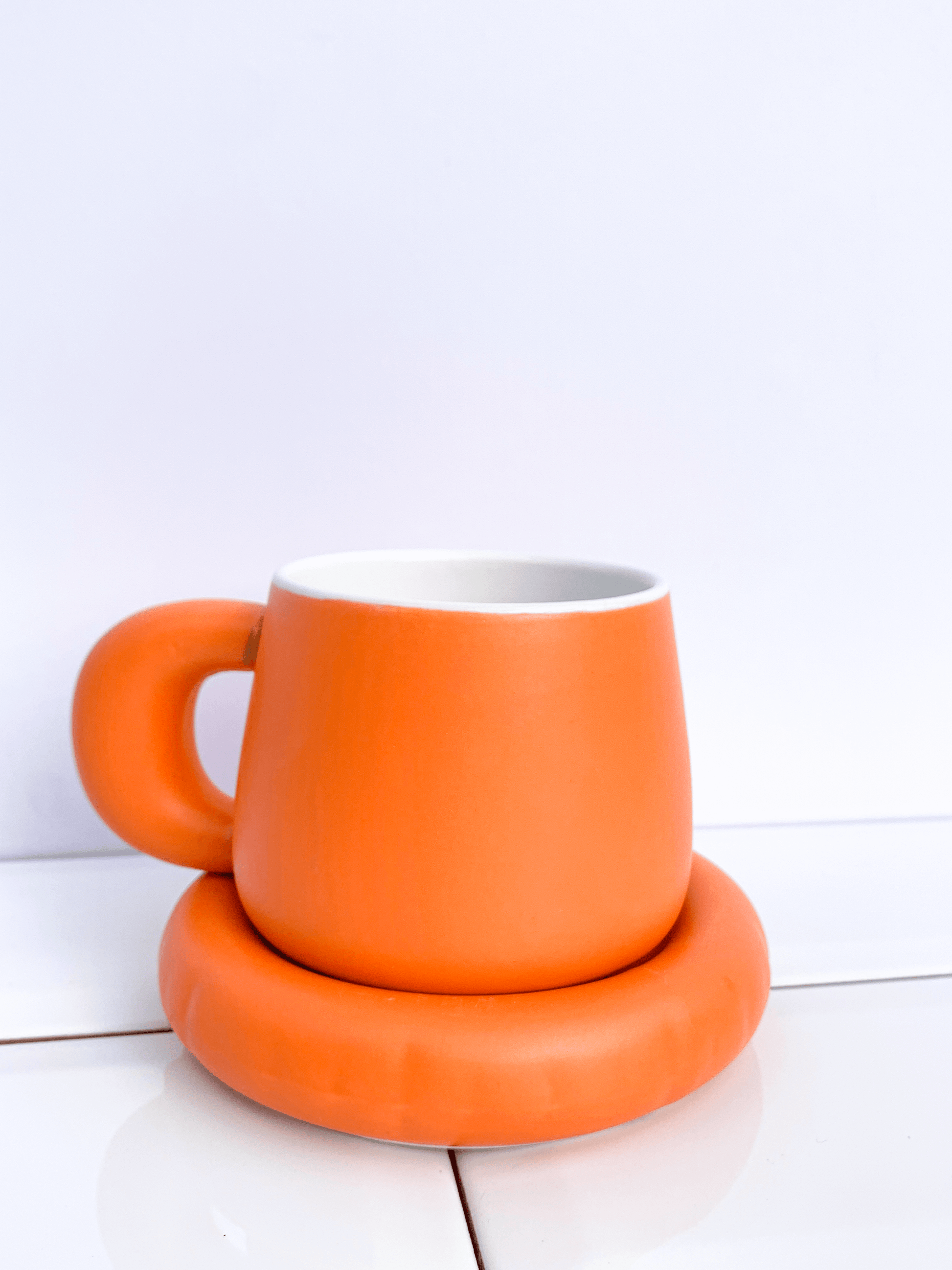 Orange ceramic cup and saucer. 