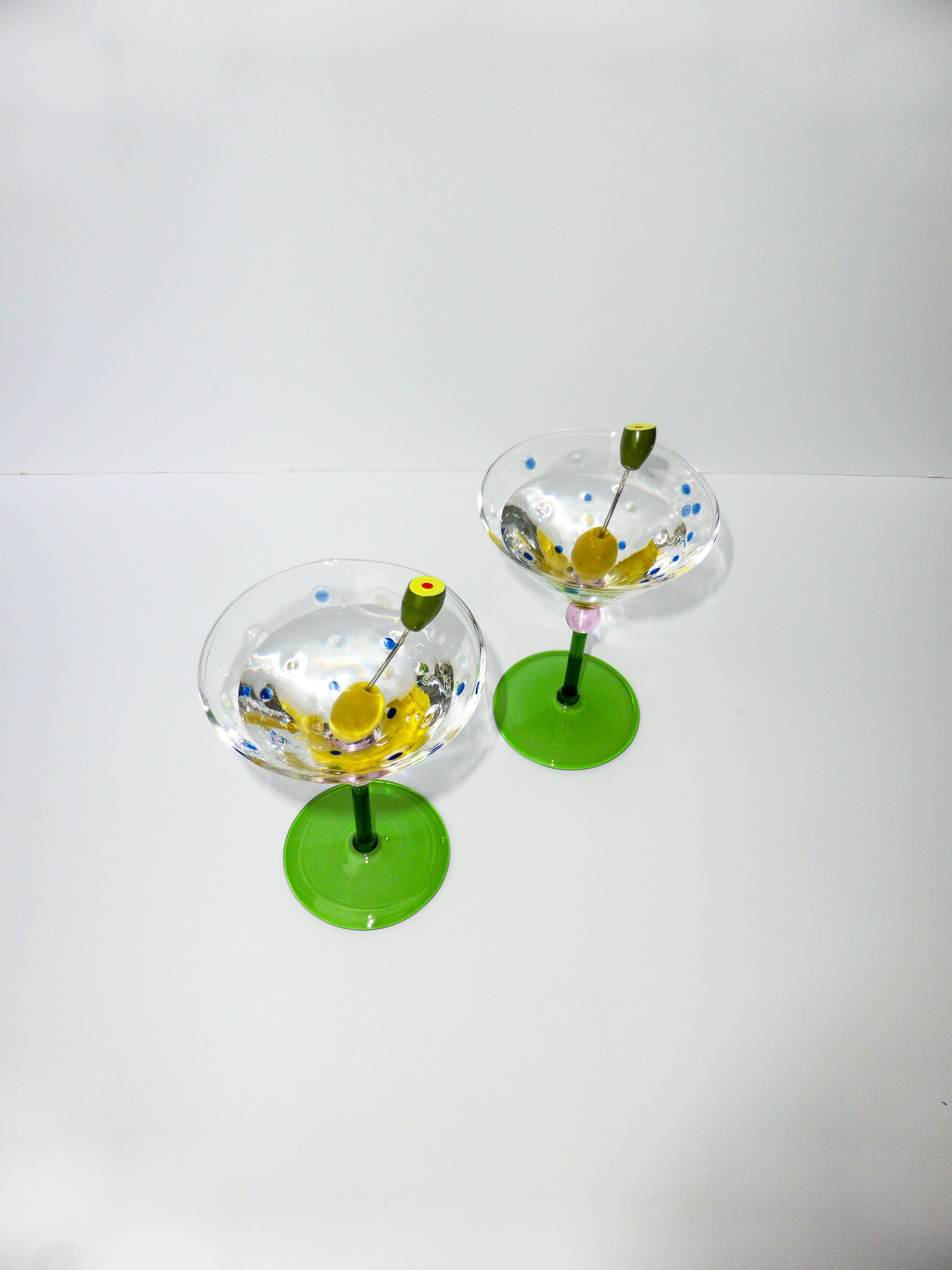 Overhead image of set of two funky martini glasses with olive pick